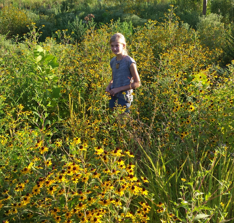 Young girl standing amongst native landscape
